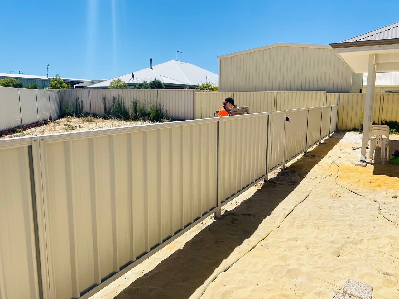 Classic Cream Colorbond side-boundary fence installed along a sandy block