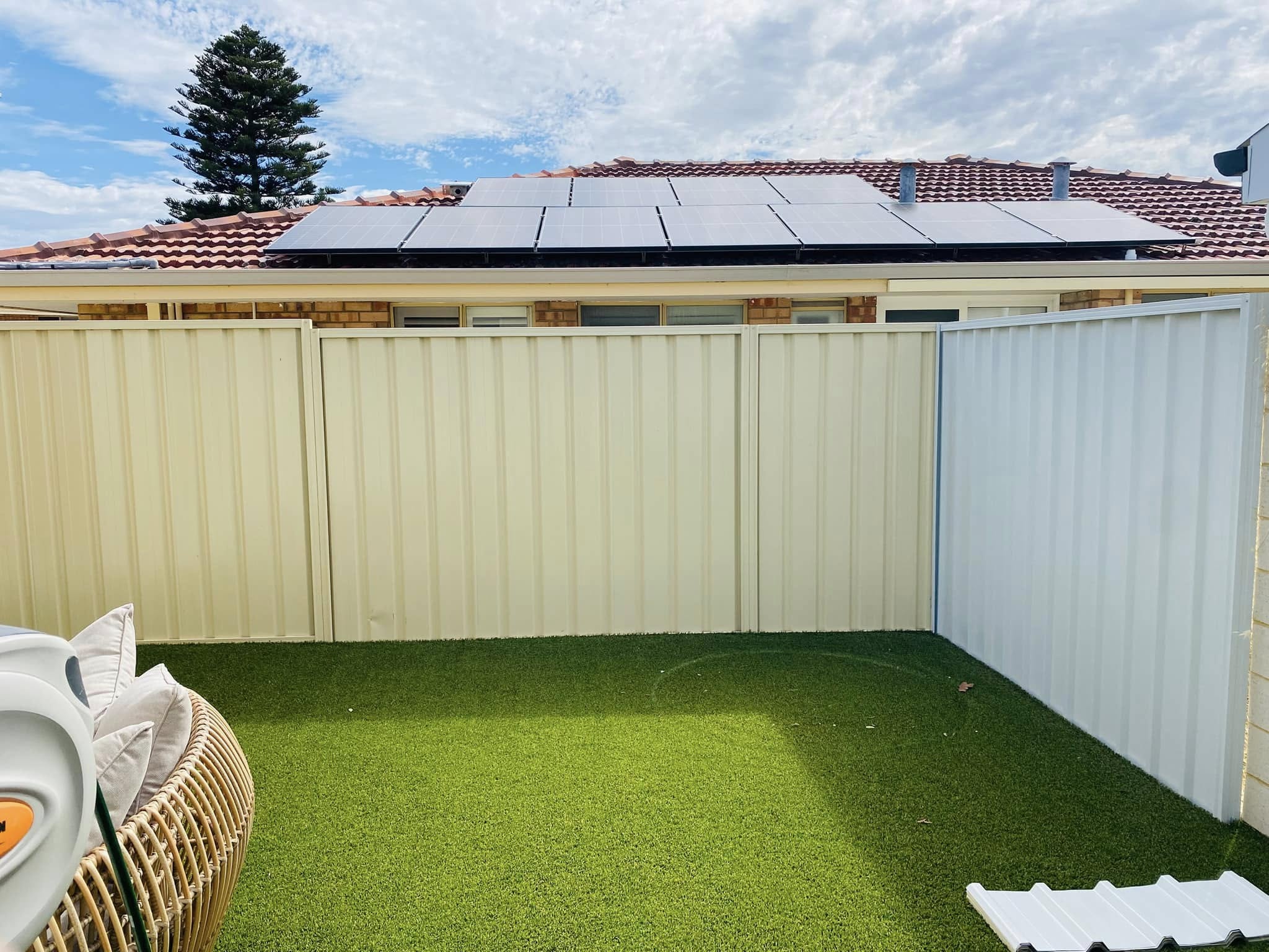 Classic Cream Colorbond boundary fence around a backyard with artificial lawn