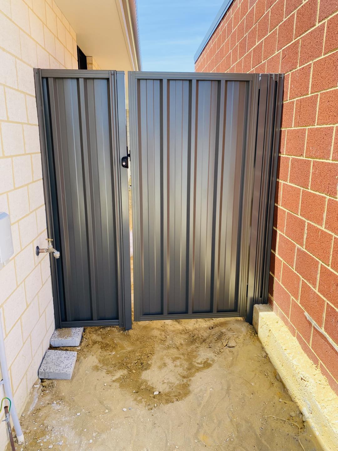 Charcoal Colorbond double side gate installed between brick walls at a Perth home