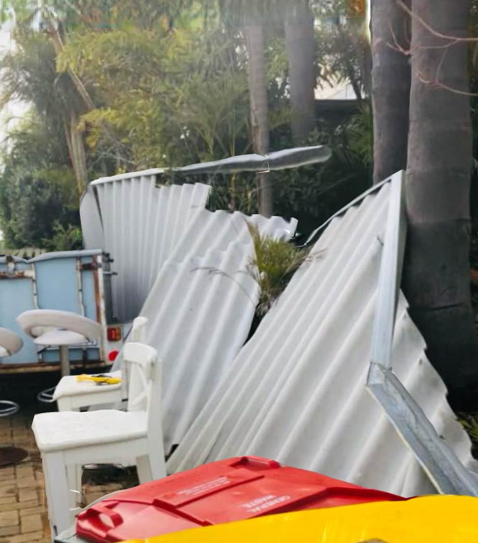 Storm-damaged corrugated fence collapsed in a Perth backyard, awaiting insurance repair